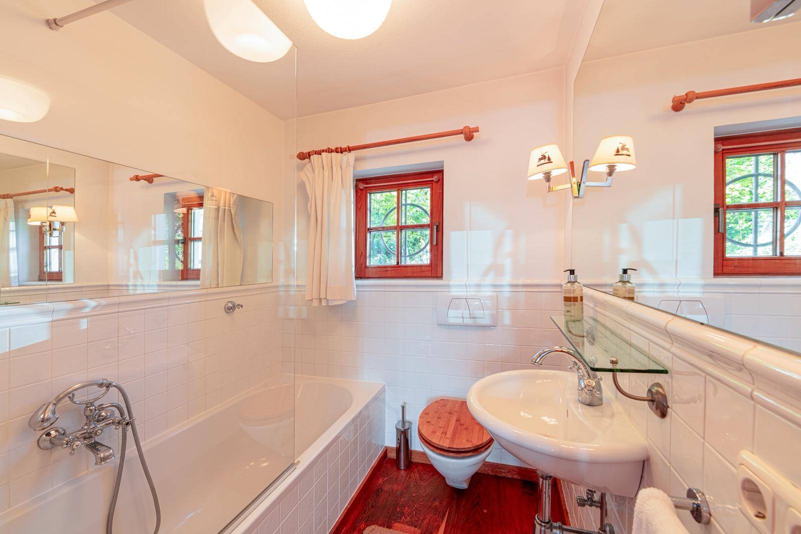 Klassisches Badezimmer mit Badewanne, Waschbecken und zwei kleinen Fenstern für Tageslicht.
