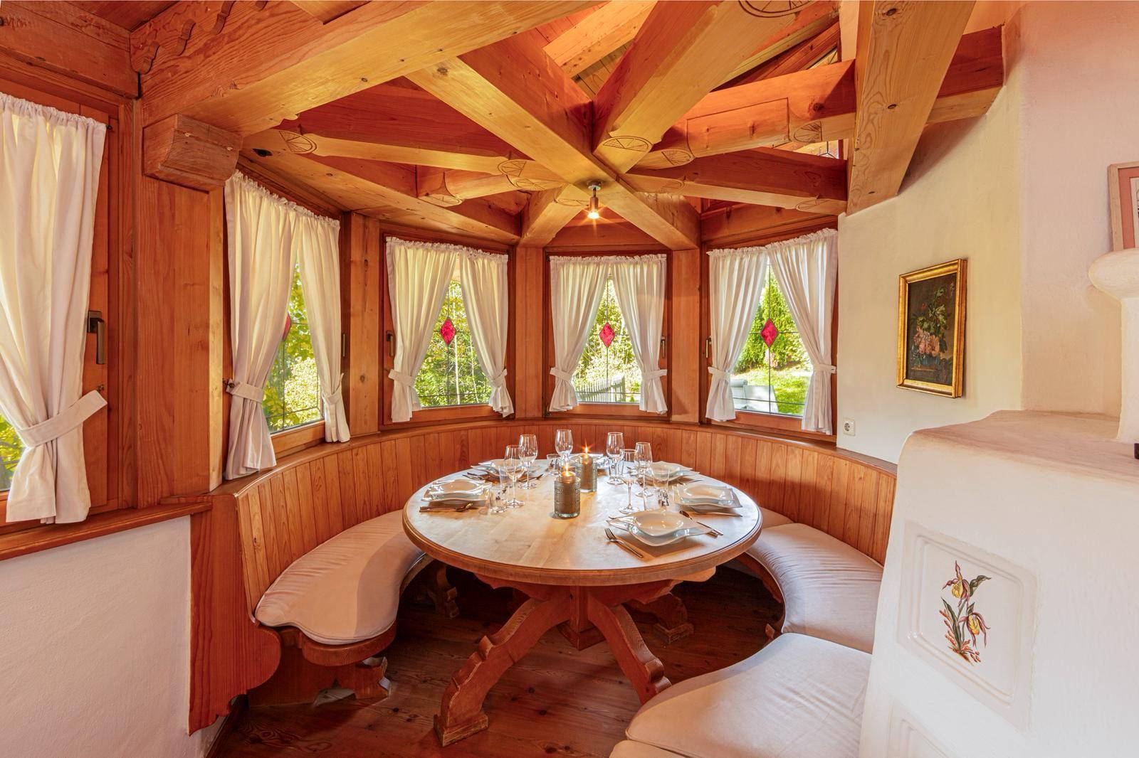 Gemütliche Essecke mit runder Holzbank, vielen Fenstern und einzigartiger Holzdeckenkonstruktion.