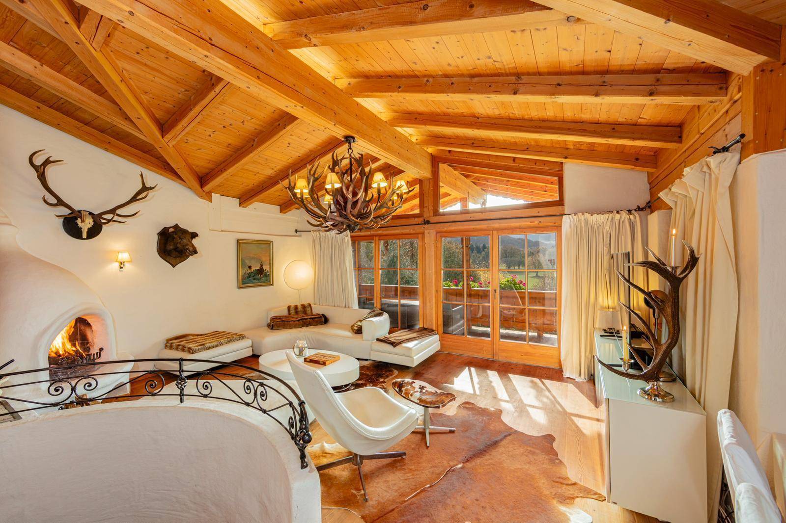 Heller Wohnbereich mit Kamin, bequemen weißen Sofas und großen Fenstern mit Bergblick.