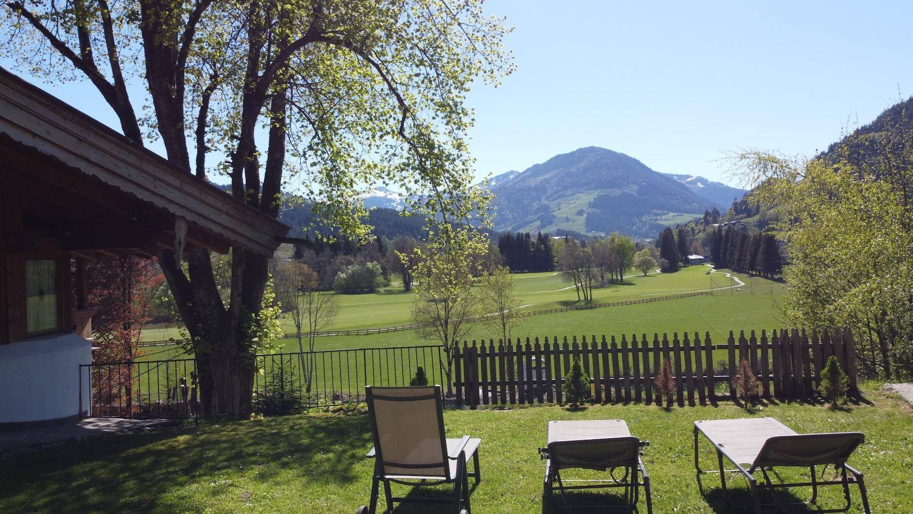 Großer Gartenbereich mit Liegestühlen und weitem Panoramablick auf Berge und grüne Wiesen.