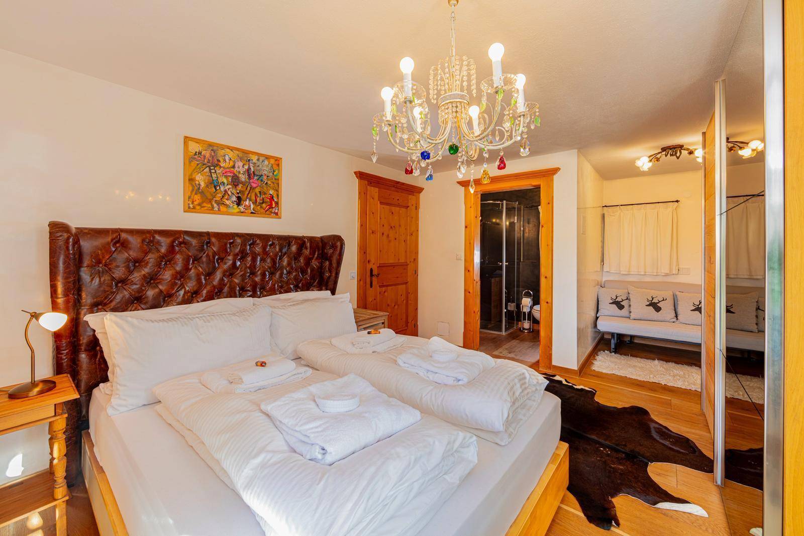 Komfortables Schlafzimmer mit großem Bett, Kronleuchter und Zugang zu einem eigenen Bad.