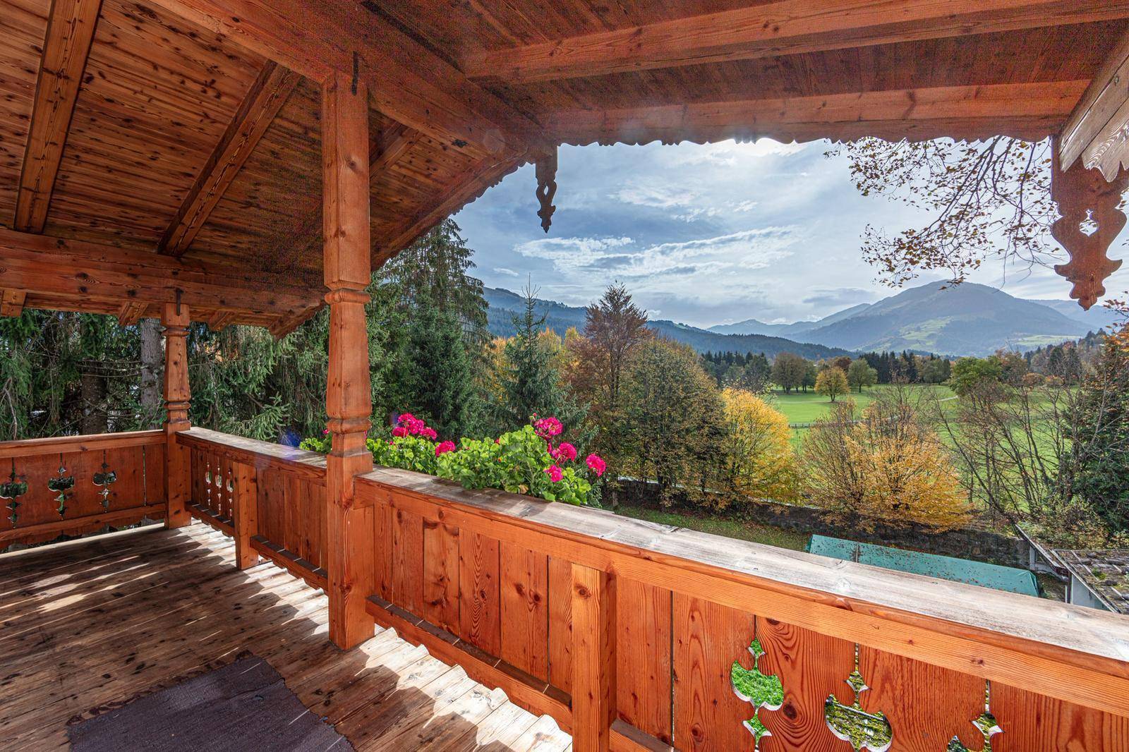 Geräumiger Holzbalkon mit Blumenkästen und weitem Blick über das Tal und die Berge.