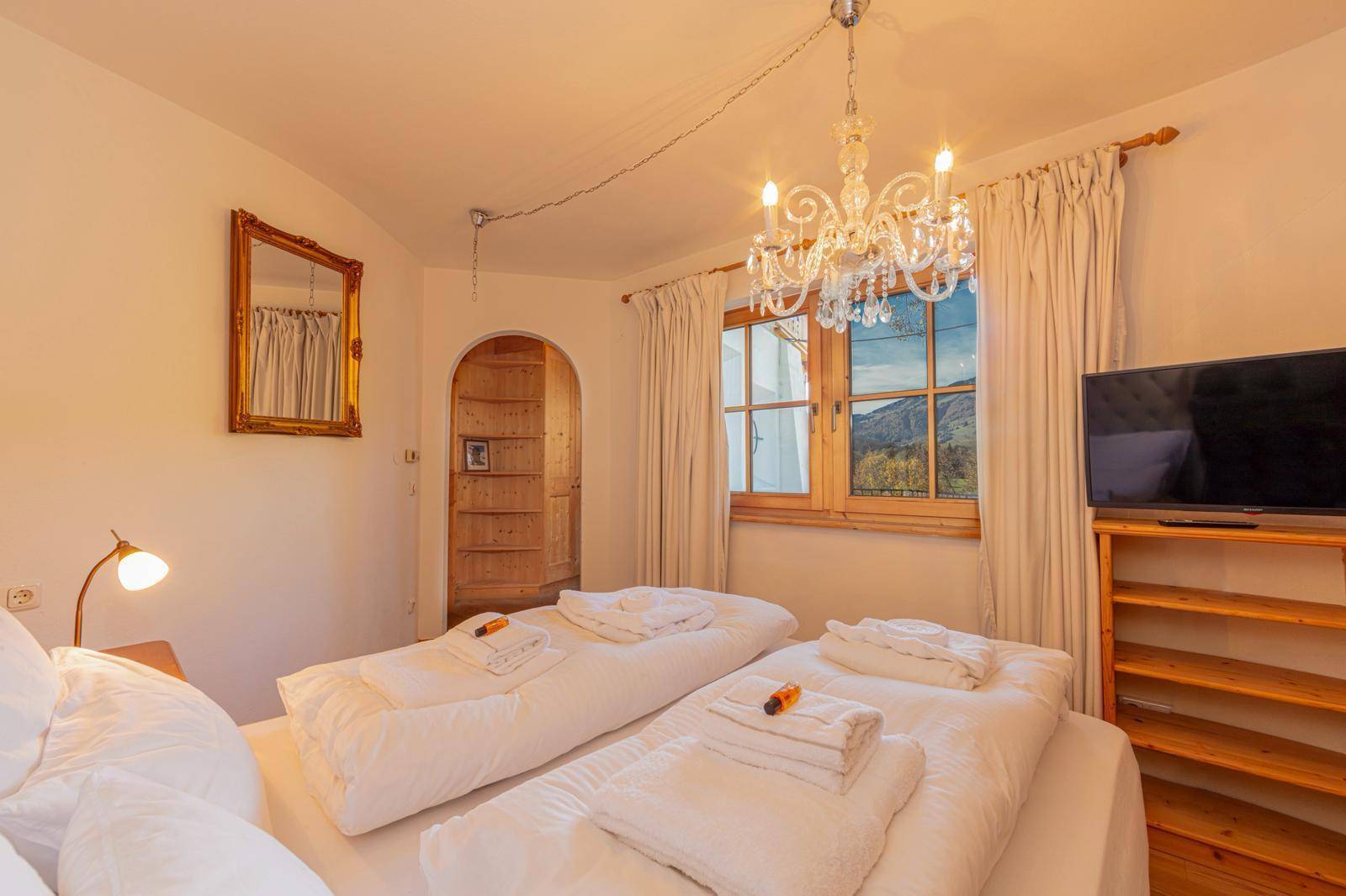 Gemütliches Schlafzimmer mit Einzelbetten, Kronleuchter und malerischem Bergblick.
