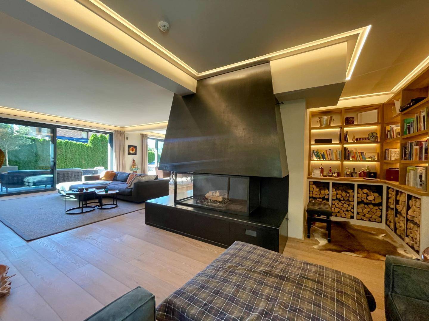 Gemütliches Wohnzimmer mit modernem Kamin, integrierten Bücherregalen und Holzlager.