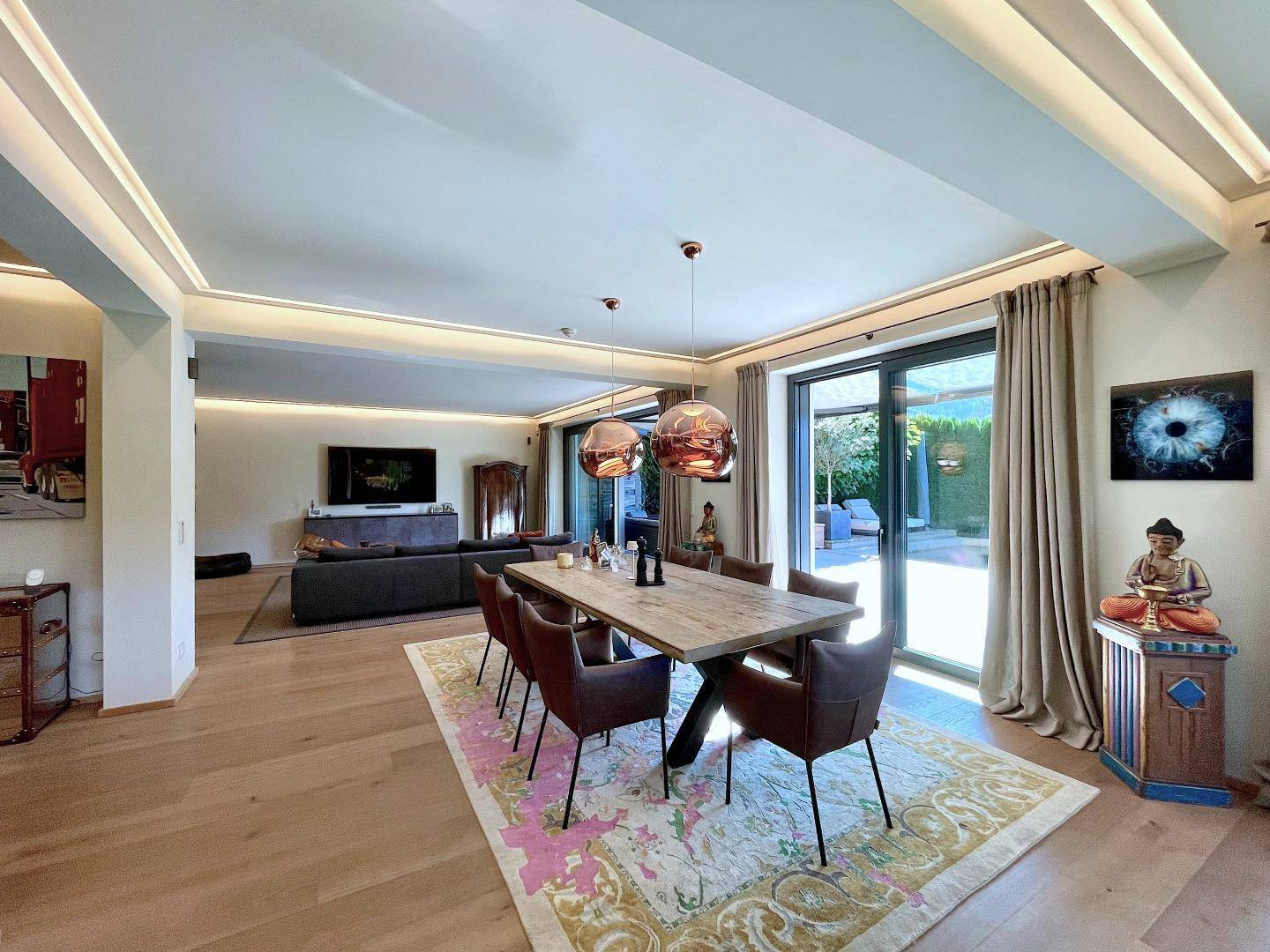 Eleganter Wohn-Essbereich mit Holzboden, großem Esstisch und Zugang zur Terrasse.