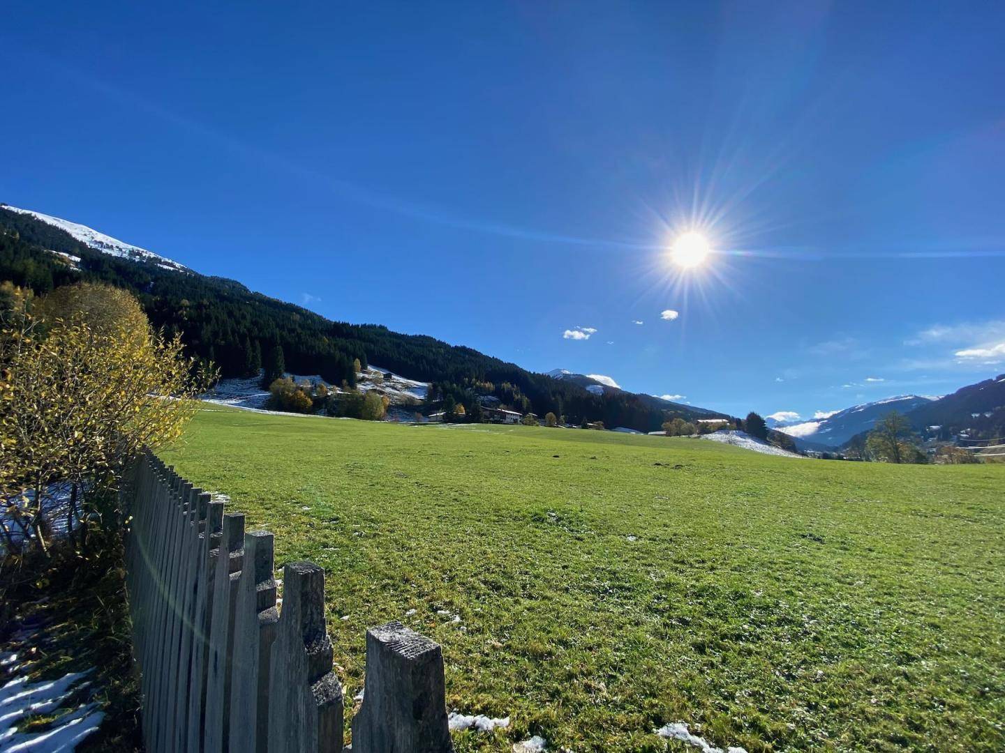 Weitläufige grüne Wiesen und Hügel unter strahlend blauem Himmel mit Sonnenschein.