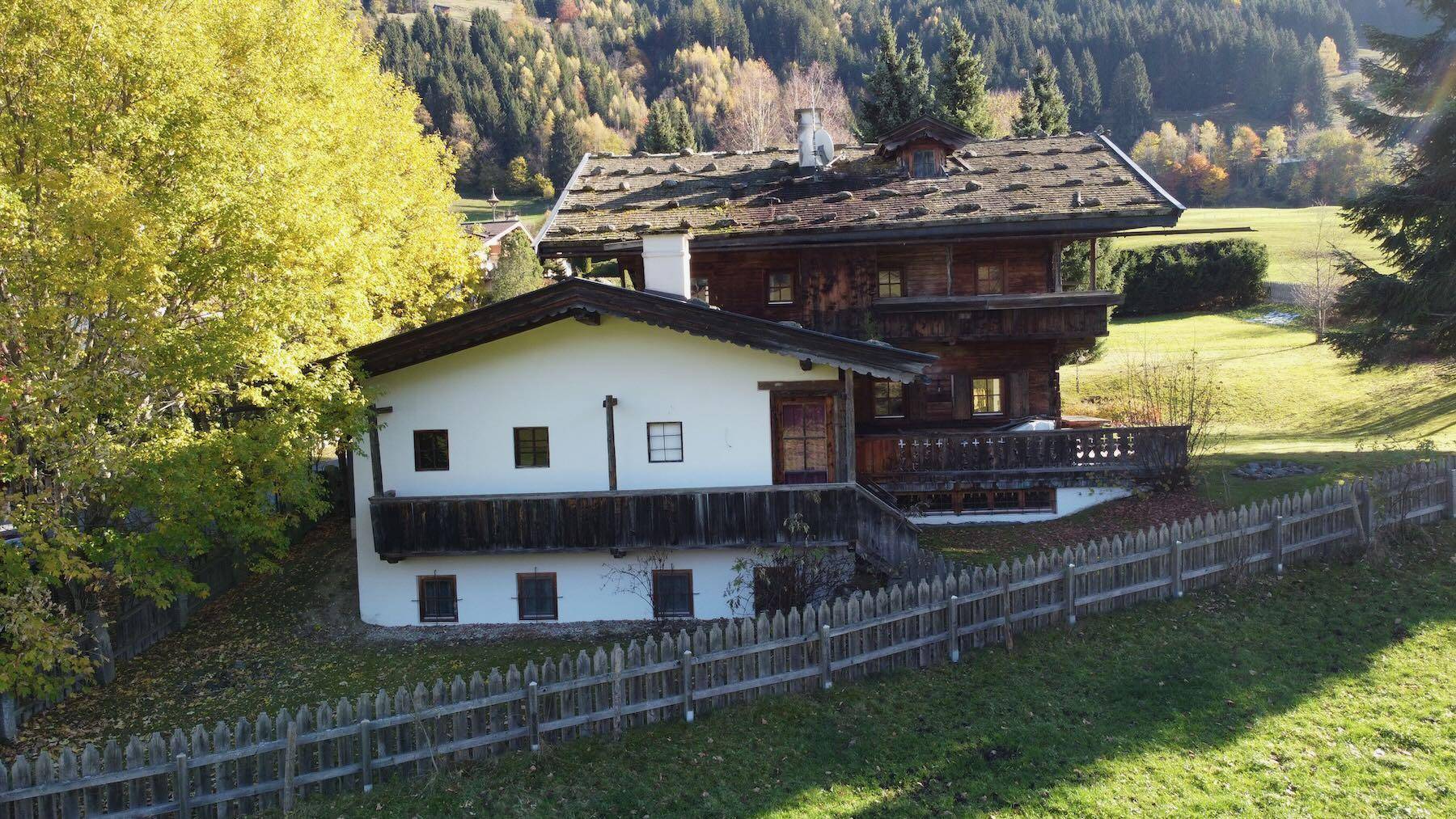 Traditionelles Holzhaus im alpinen Stil mit Satteldach und umgebender Naturlandschaft.