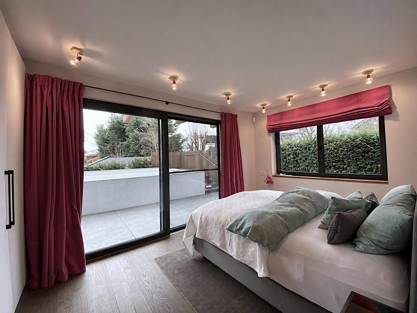 Helles Schlafzimmer mit Zugang zur Terrasse, großen Schiebetüren und farbigen Vorhängen.