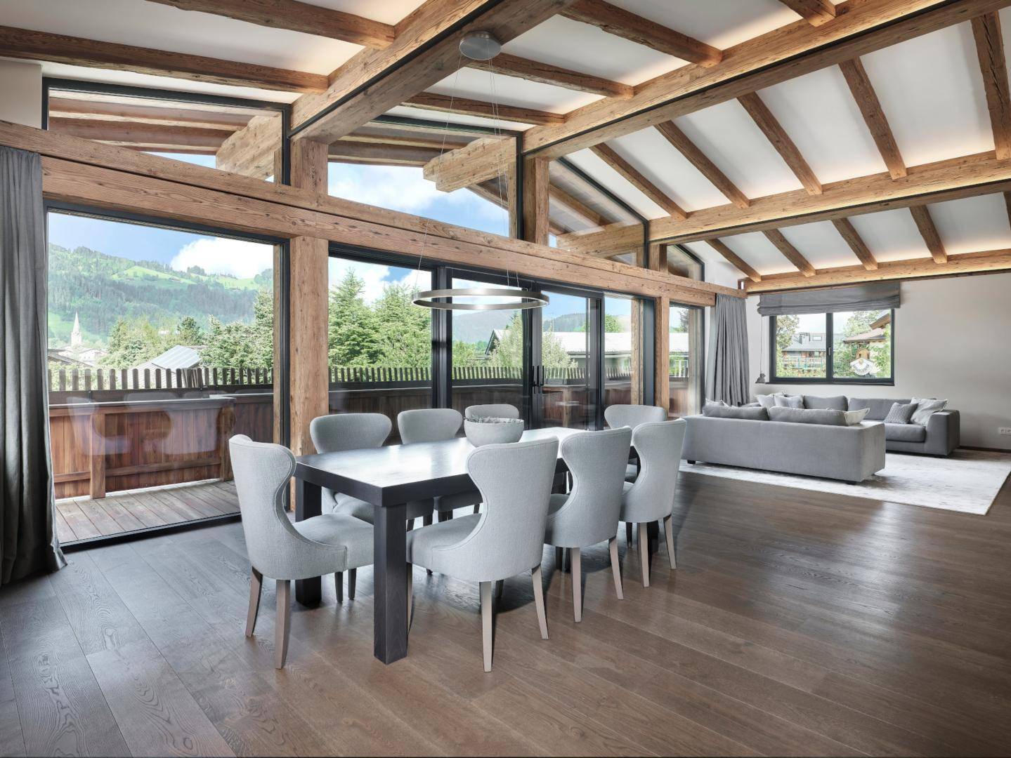 Heller Wohn-Essbereich mit Holzbalkendecke, großen Fenstern und Bergblick, modern eingerichtet.