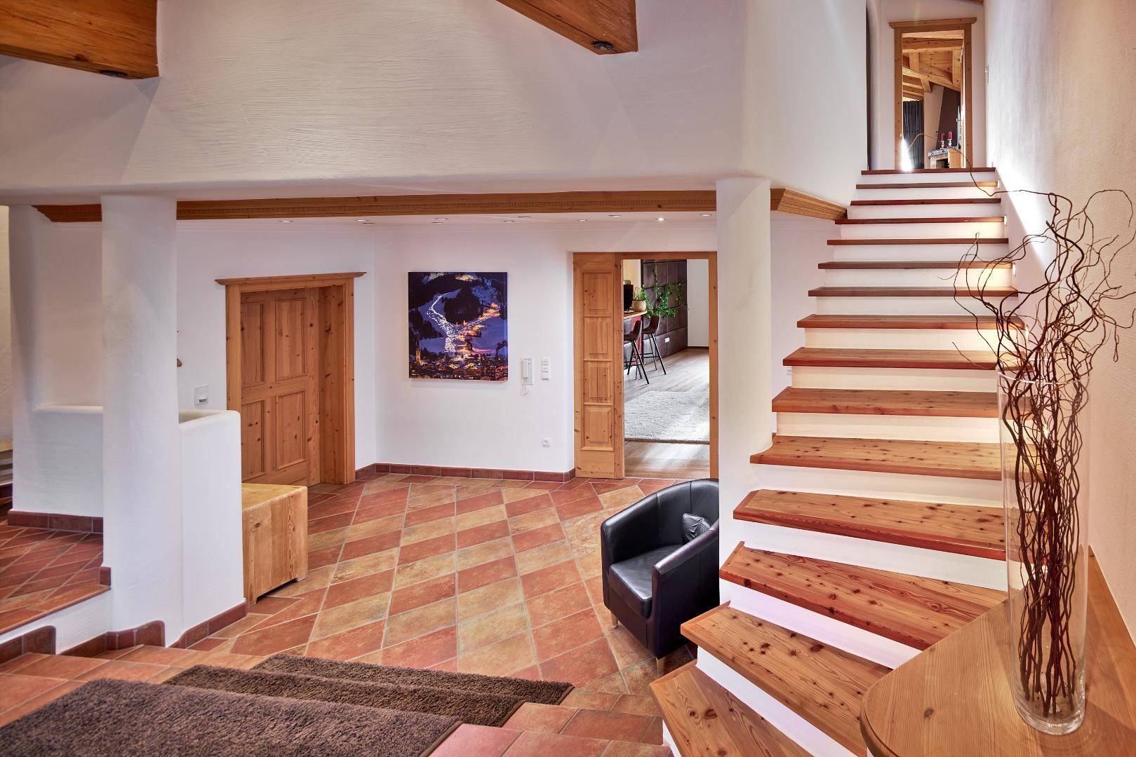 Geräumiger Eingangsbereich mit rustikalen Holztreppen, Terrakotta-Fliesenboden und Holztüren.