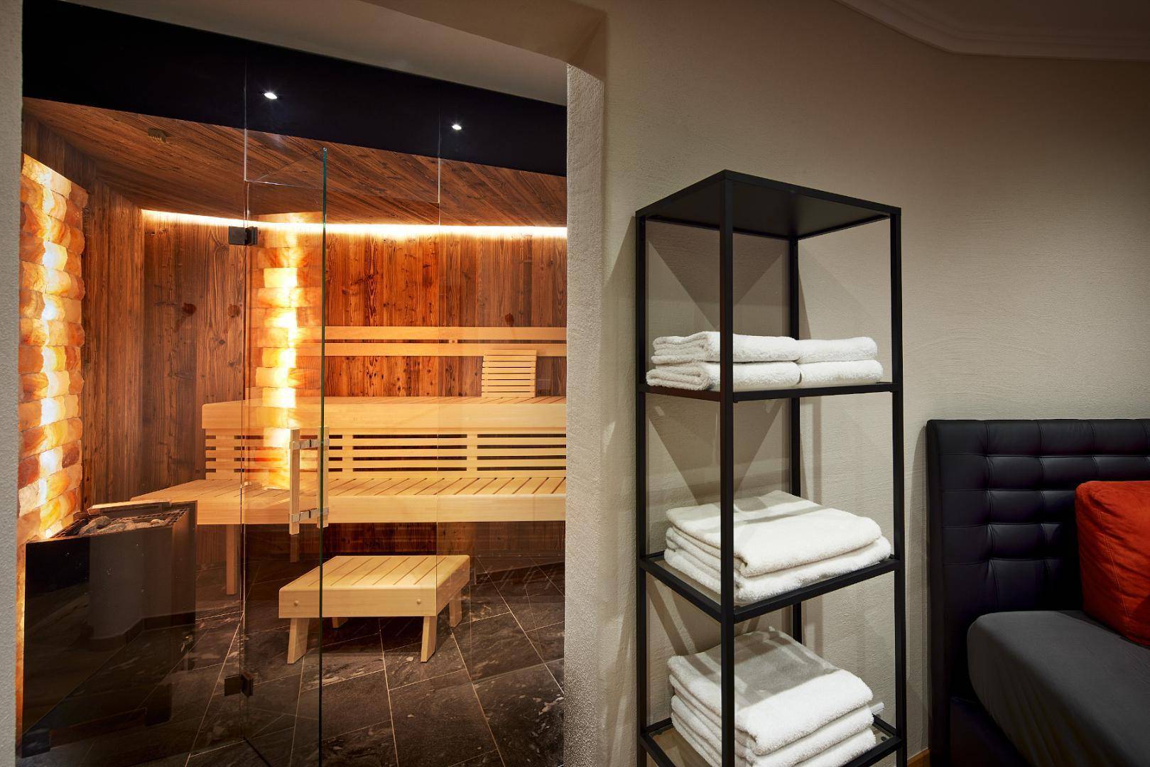 Moderne Sauna mit Holzbänken, Salzwand und angrenzendem Entspannungsbereich.