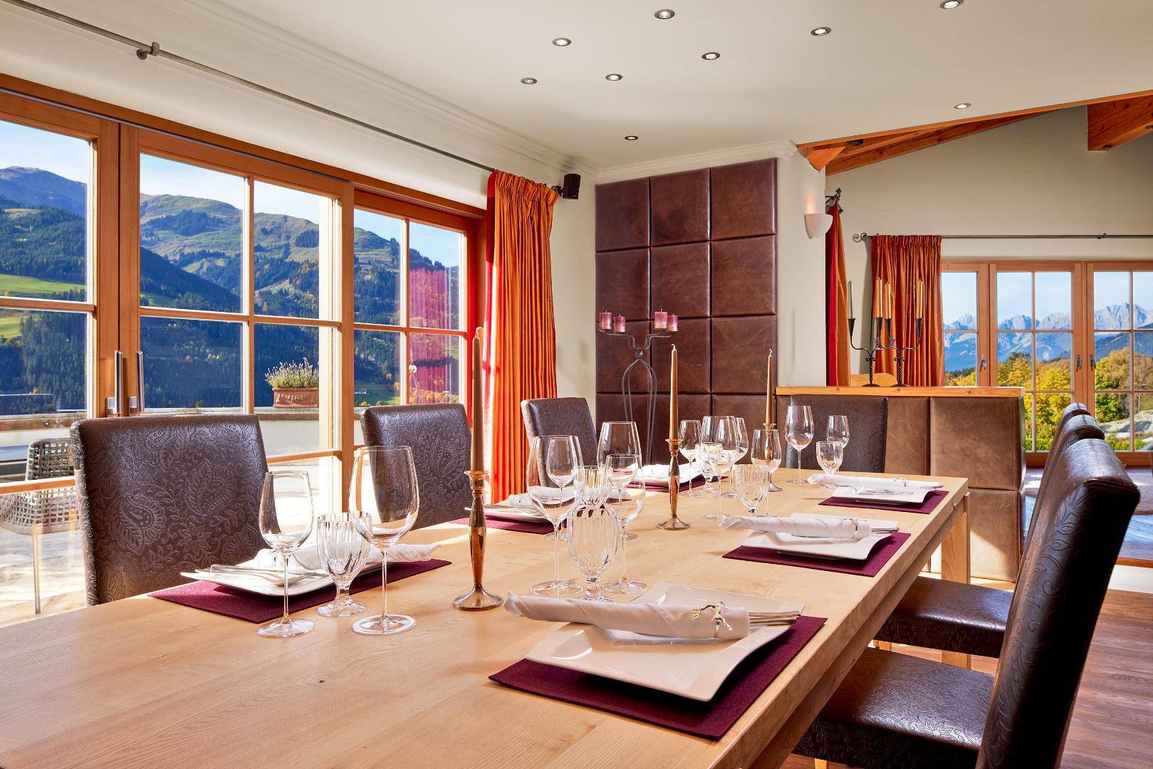 Heller Essbereich mit großem Holztisch, eleganten Gedecken und Panoramablick auf die Berge.