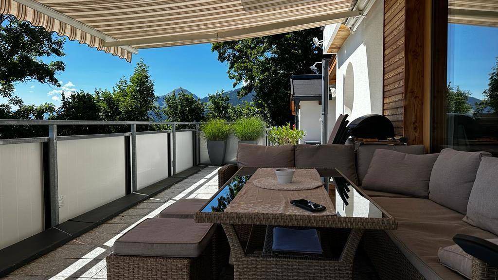 Gemütlicher Balkon mit Rattanmöbeln und einem Glastisch, ideal zum Entspannen im Freien.