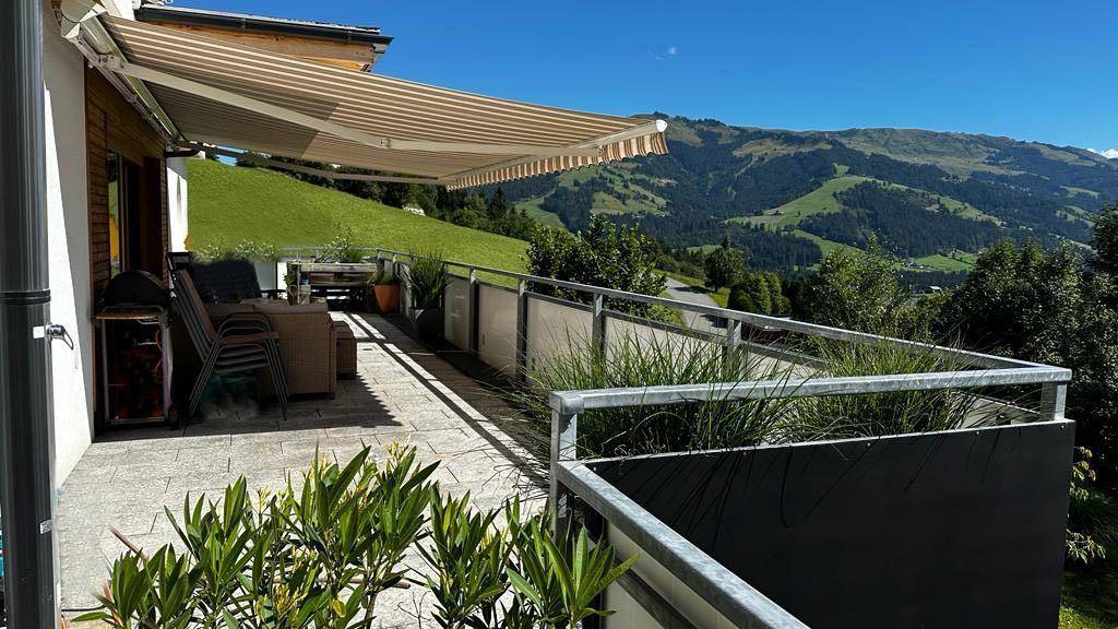 Sonniger Balkon mit Markise, bequemen Sitzgelegenheiten und herrlichem Bergblick.