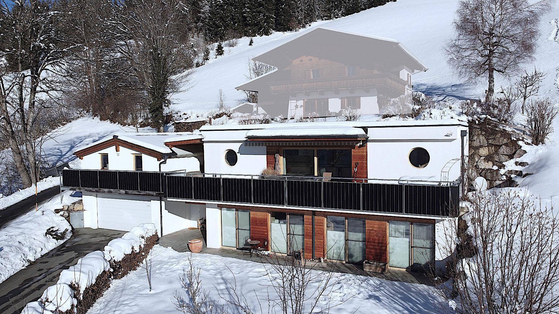 Modernes Haus in winterlicher Berglandschaft mit verschneiten Balkonen und Umgebung.