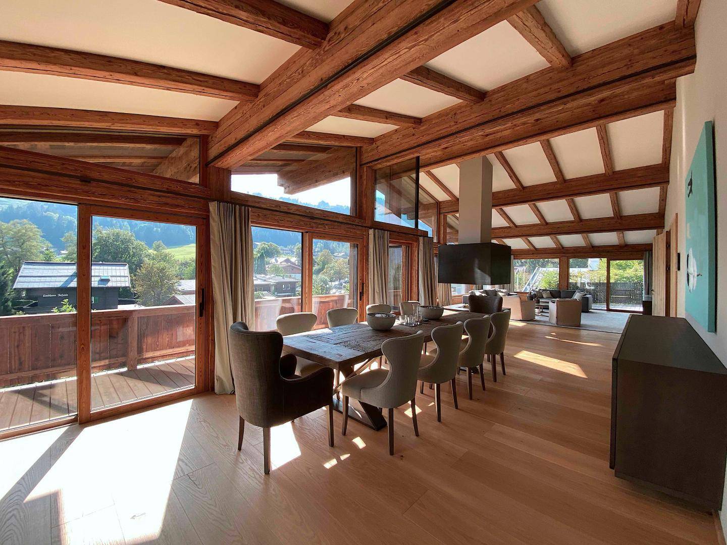 Heller Essbereich mit großem Holztisch, Holzbalken und Zugang zum Balkon mit Bergblick.