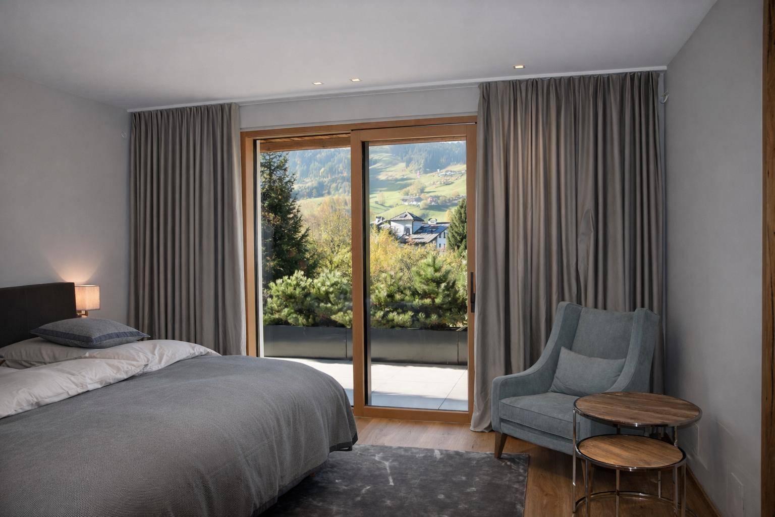 Gemütliches Schlafzimmer mit Zugang zur Terrasse und malerischem Blick auf die grüne Landschaft.