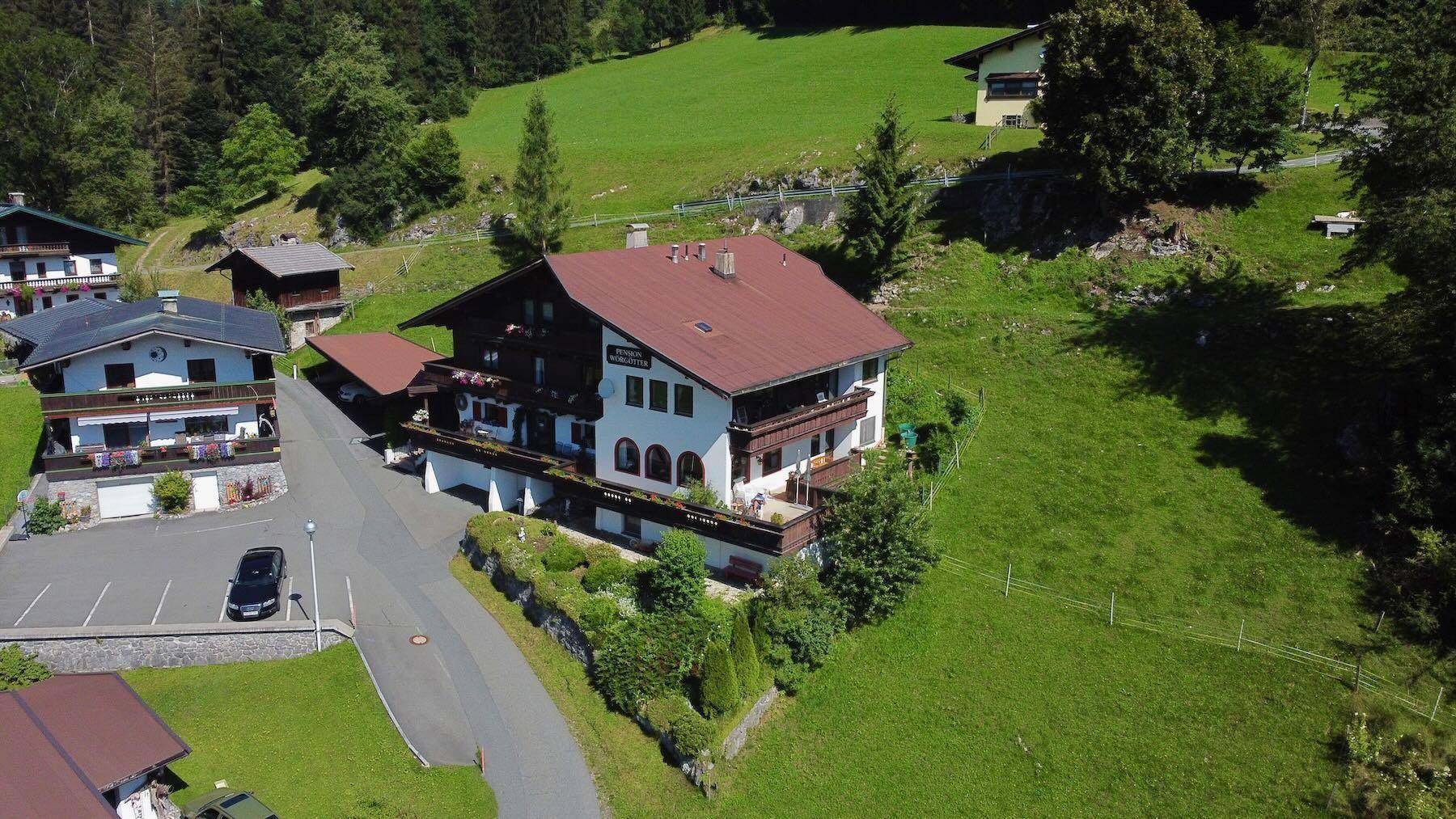 Panoramablick auf ein charmantes alpines Anwesen, umgeben von weiteren Häusern und Natur.