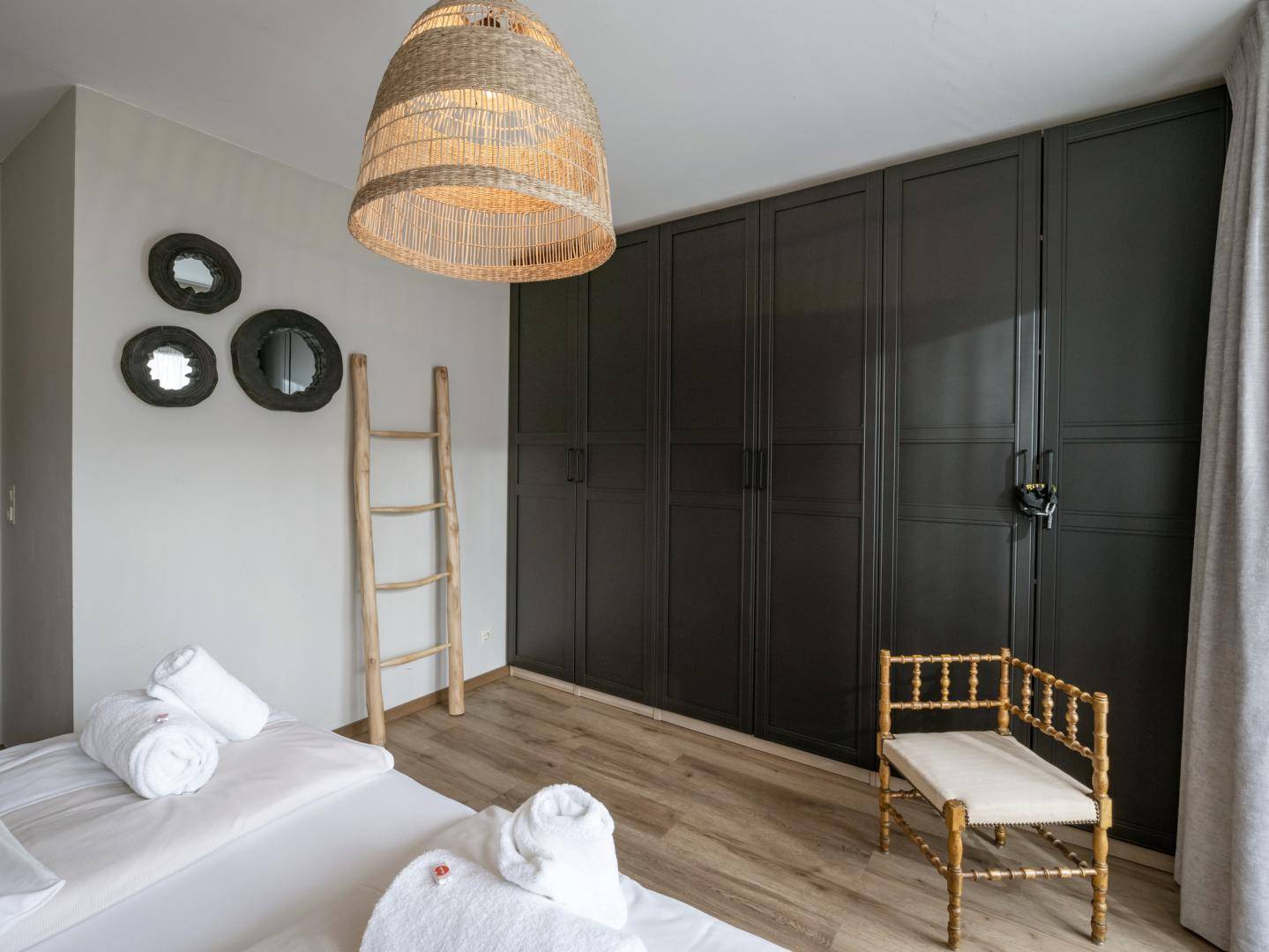 Schlafzimmer mit Einbauschränken in dunklem Design und Holzboden, bietet viel Stauraum.