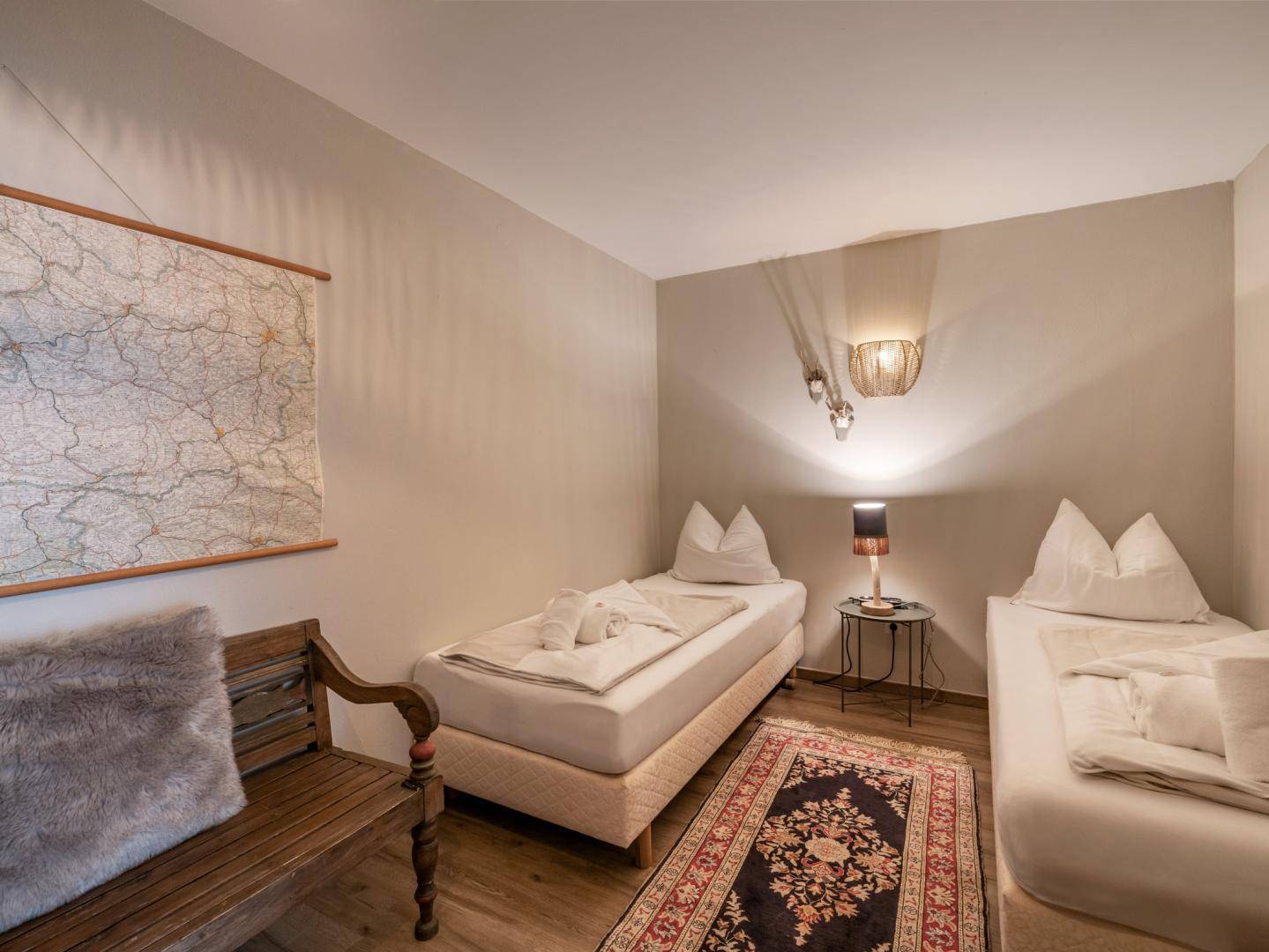 Gemütliches Schlafzimmer mit zwei Einzelbetten, Holzboden und traditionellem Teppich.