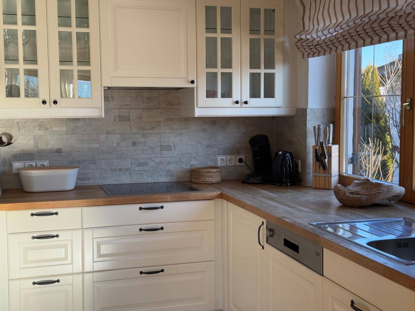 Moderne Einbauküche mit weißen Fronten, Holz-Arbeitsplatten und Induktionskochfeld.