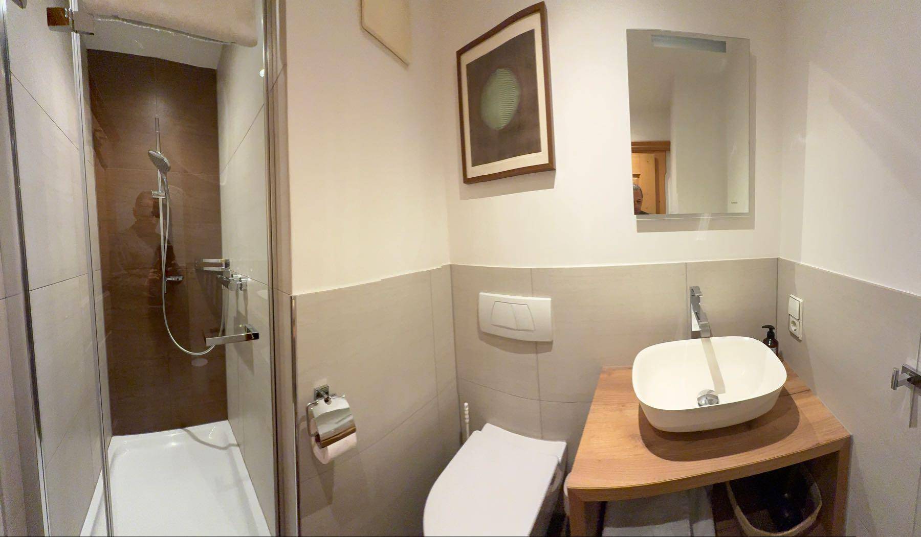 Modernes Badezimmer mit Dusche, wandhängendem WC und Aufsatzwaschbecken.