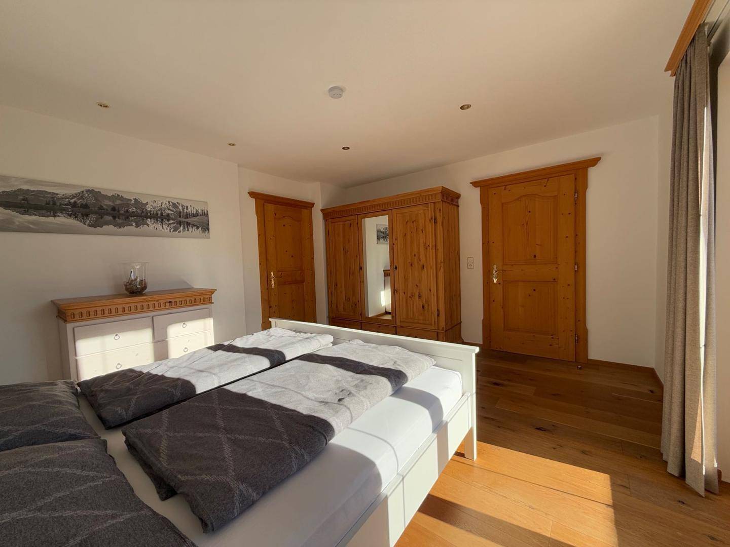 Schlafzimmer mit Holzboden, Doppelbett und rustikalen Holzschränken.