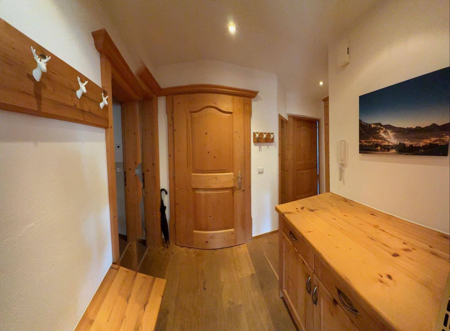 Heller Flur mit Holzboden, Garderobe und rustikalen Holztüren.
