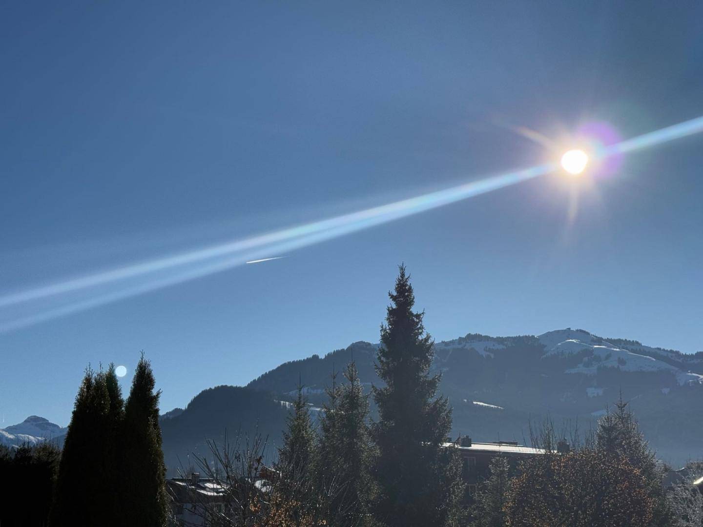 Sonniger Bergblick mit grünen Bäumen und klarem Himmel.