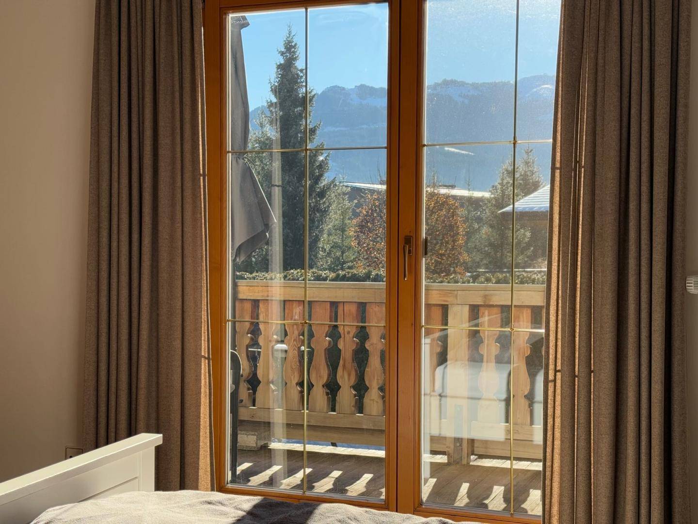 Fenster im Schlafzimmer mit Blick auf die Berge und den Balkon.