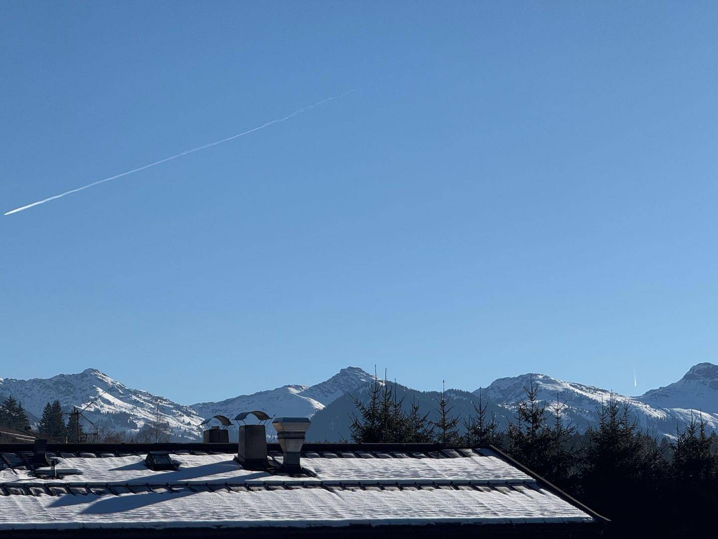 Panoramablick auf schneebedeckte Berge und einen klaren blauen Himmel.