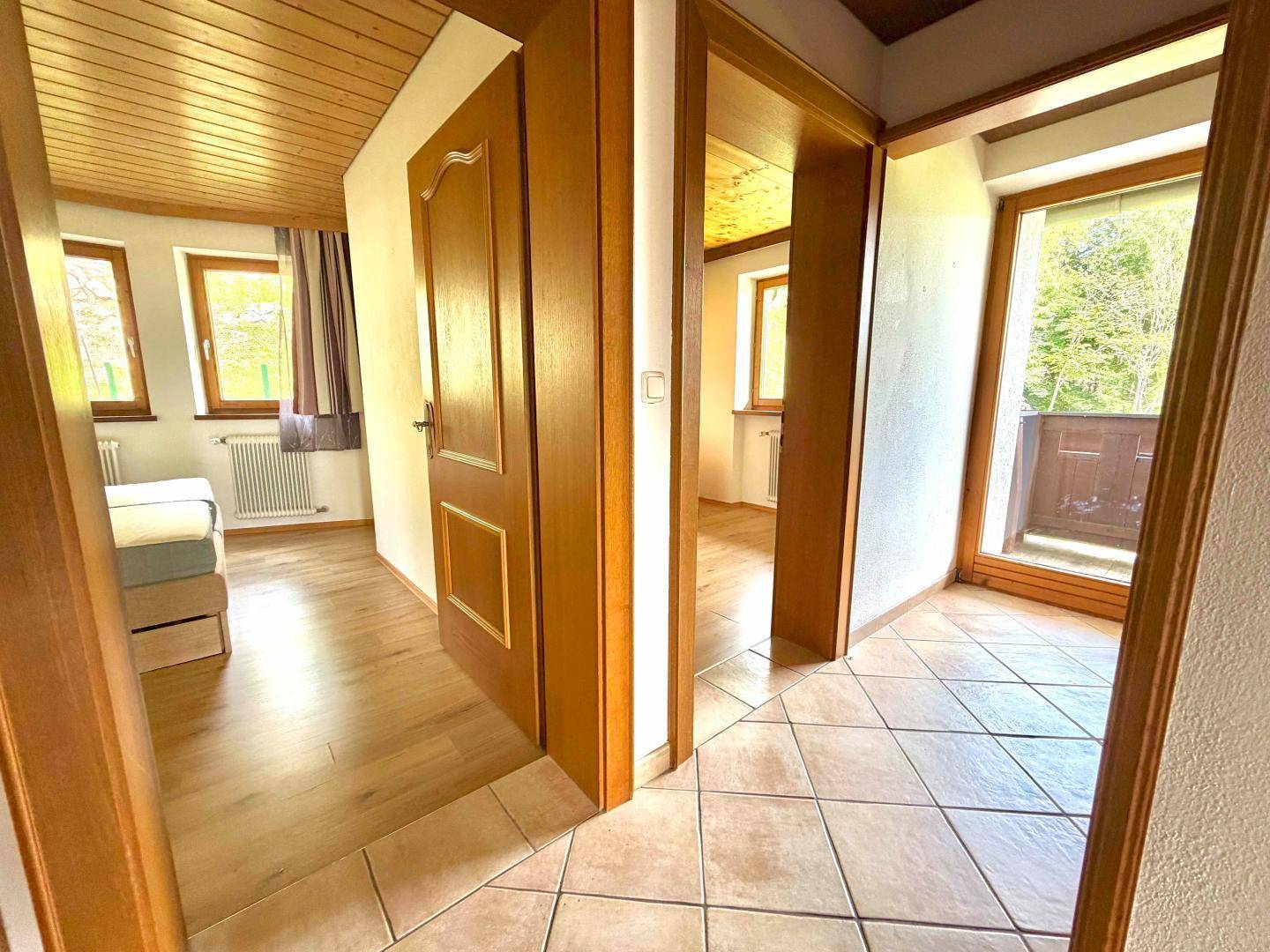 Heller Flur mit Fliesenboden, Holztüren und Zugang zu weiteren Räumen sowie einem Balkon.