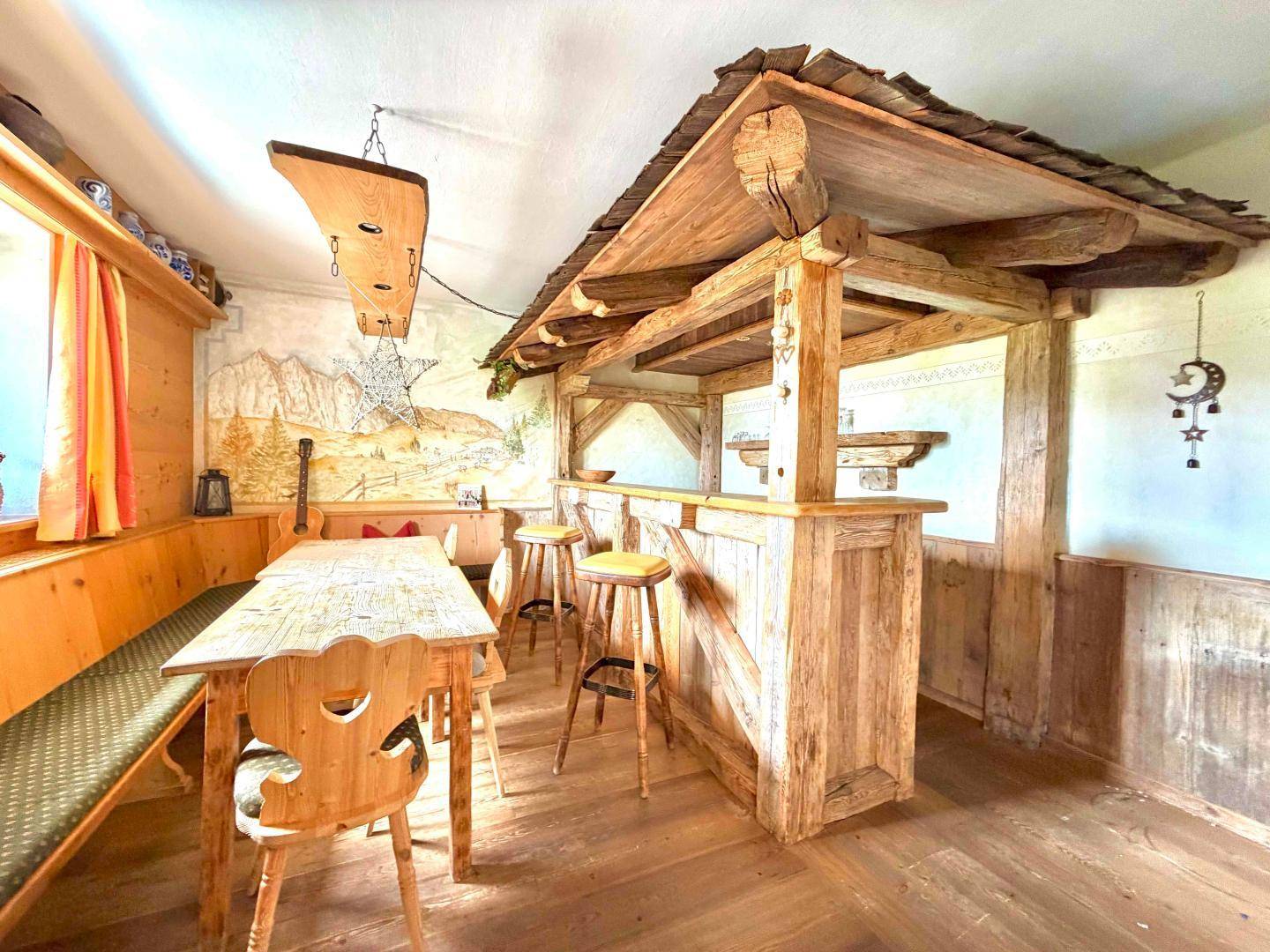 Rustikale Bar im alpenländischen Stil mit Holzelementen, Barhockern und traditioneller Wanddekoration.