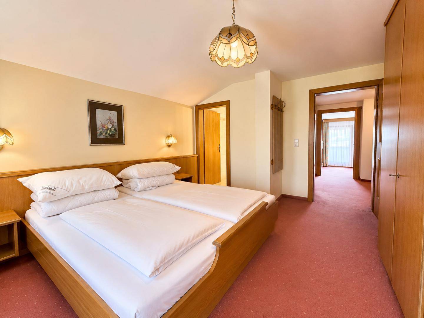 Helles Schlafzimmer mit Doppelbett, Teppichboden und Holzschränken.
