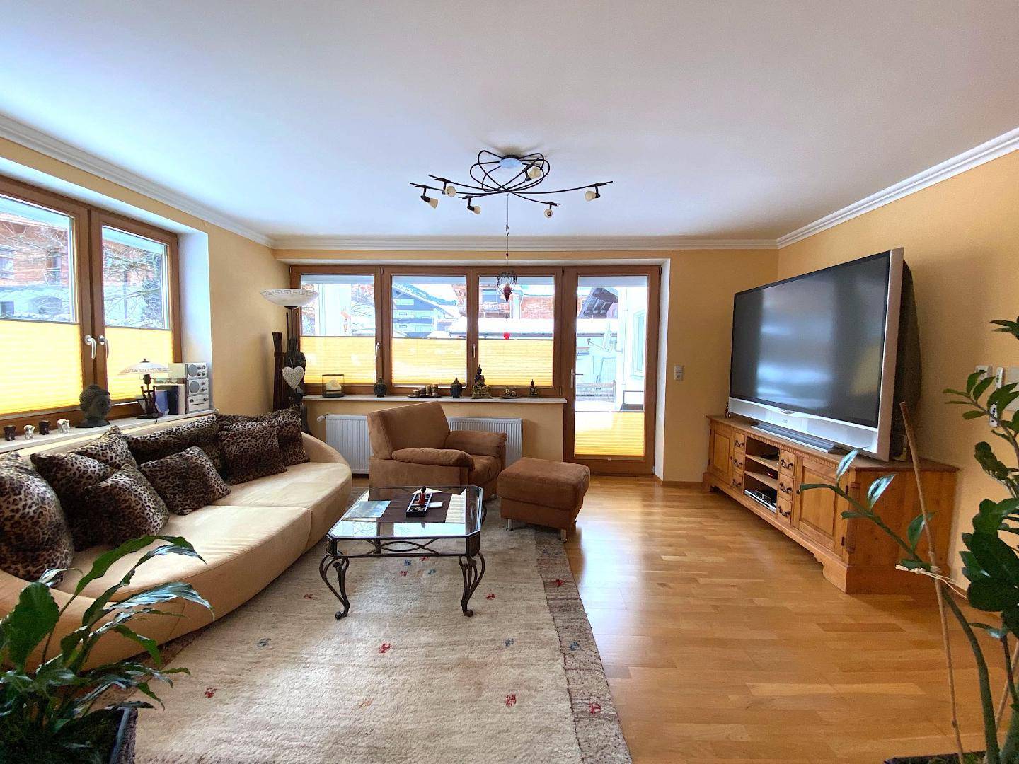 Heller Wohnbereich mit beigem Sofa, Holzboden und Zugang zu einem Außenbereich.