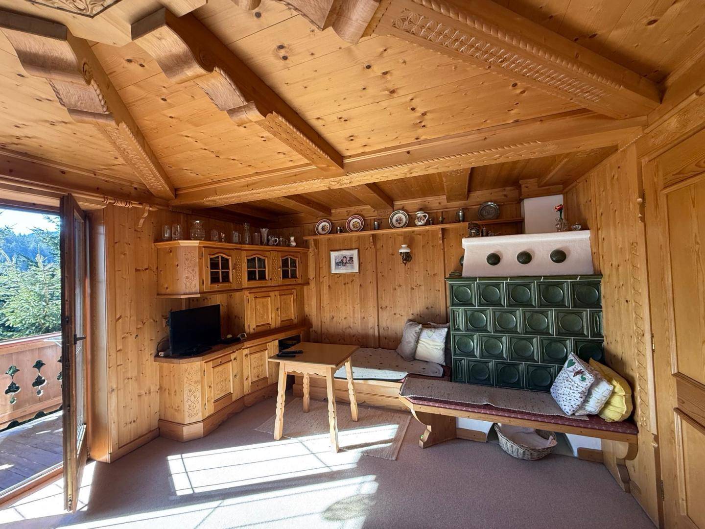Gemütliches Wohnzimmer im alpinen Stil mit Holztäfelung, Kachelofen und traditionellen Sitzgelegenheiten.