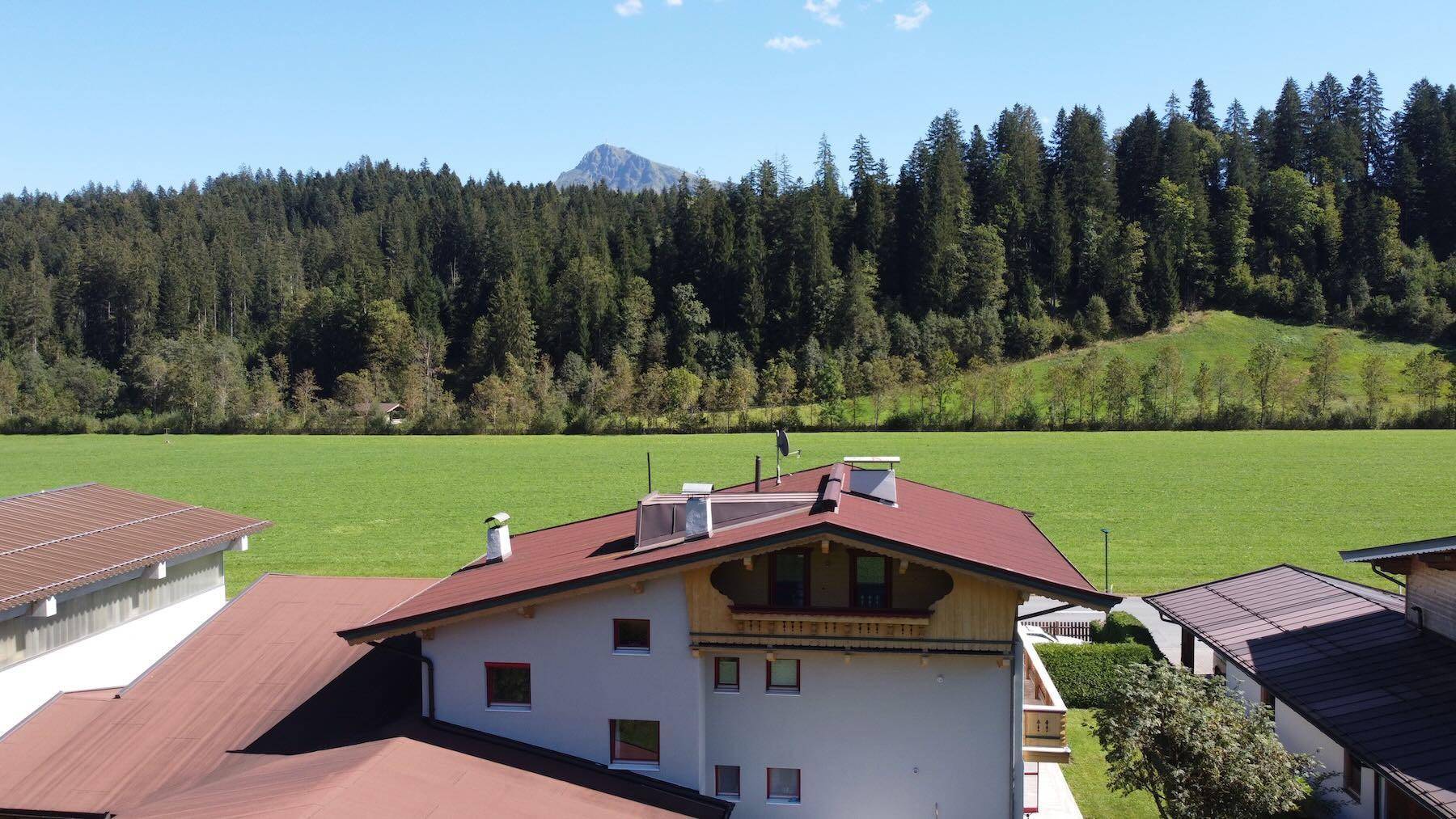 Dachansicht des Hauses mit weitem Blick über grüne Felder, bewaldete Hügel und einen Berg.
