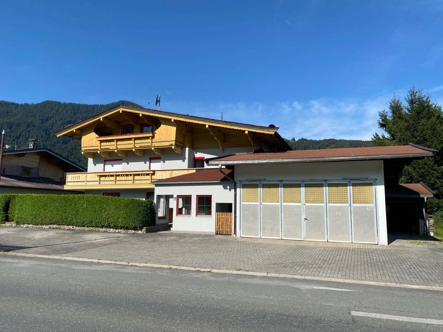 Traditionelles Haus im alpinen Stil mit Holzelementen, Balkonen und einer großen Garagenfront.