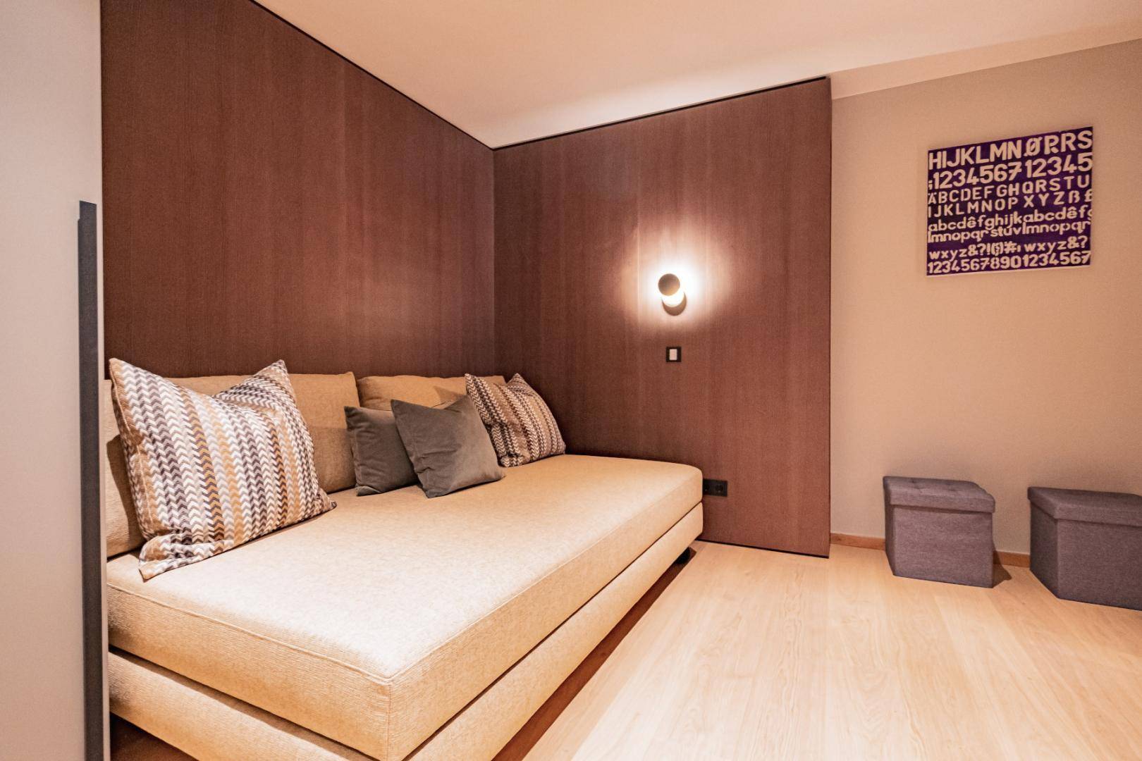 Gemütlicher Raum mit Tagesbett, Holzwandverkleidung und weichem Teppich, ideal als Gästezimmer.