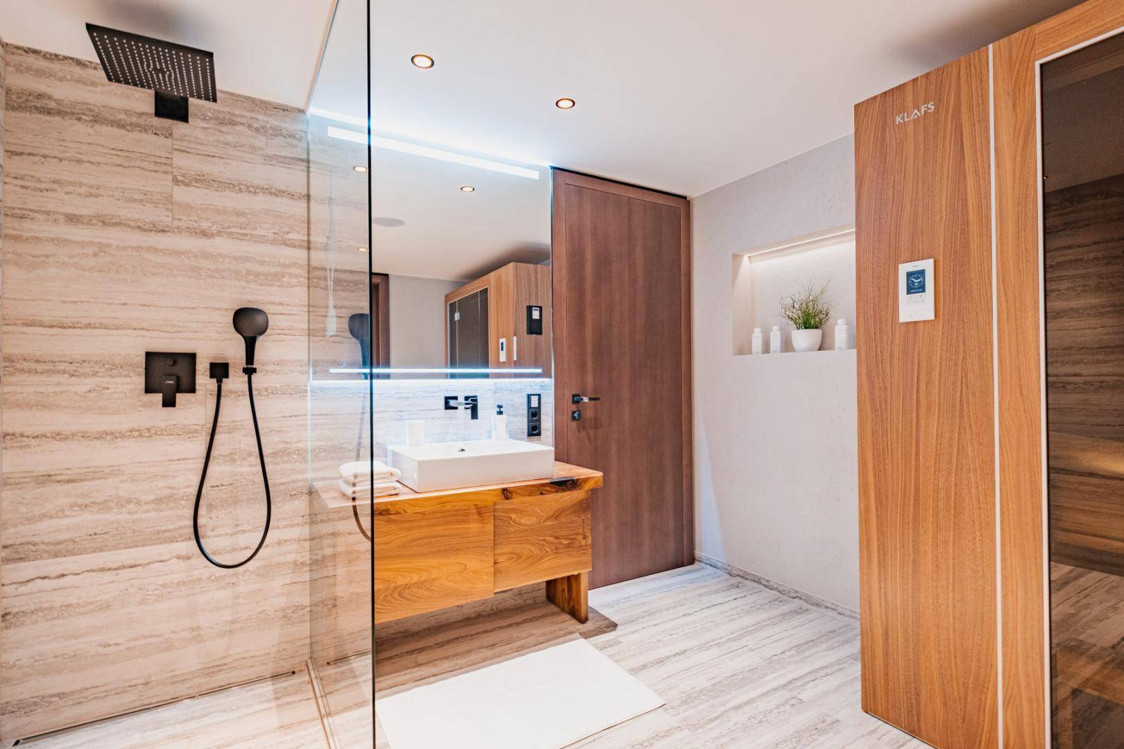 Modernes Badezimmer mit begehbarer Dusche, Holzwaschtisch und integrierter Sauna für Wellness.