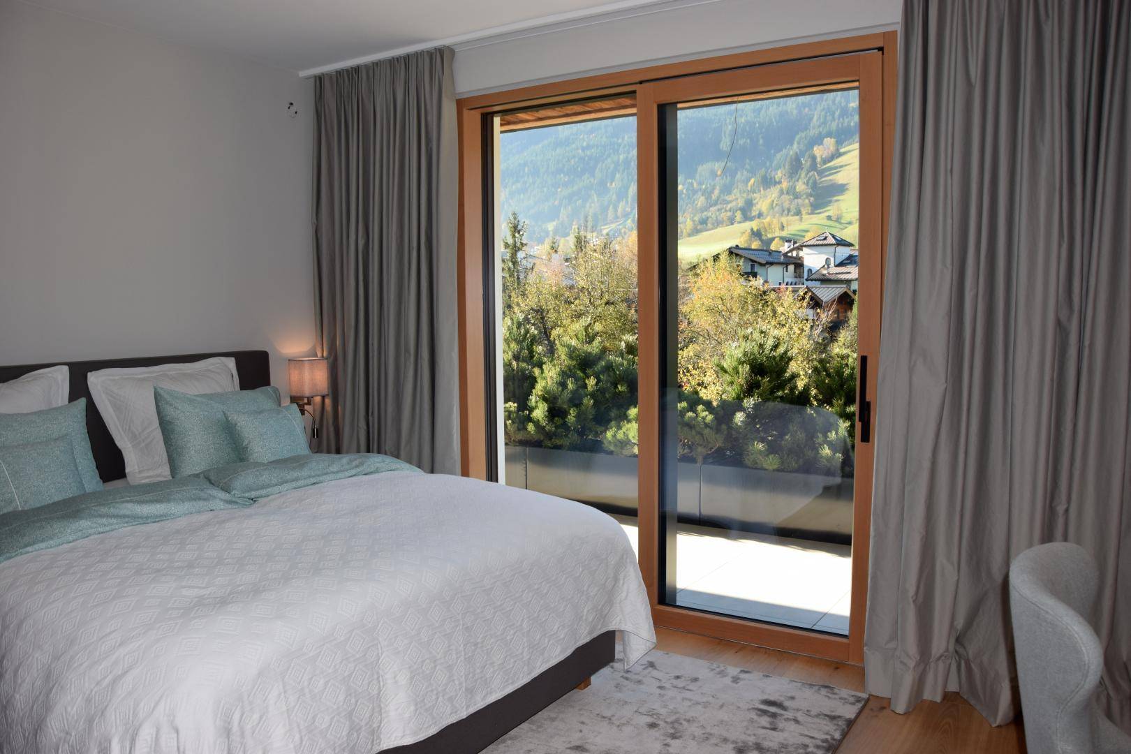 Komfortables Schlafzimmer mit Holzboden und weitem Blick auf die umliegende Berglandschaft.
