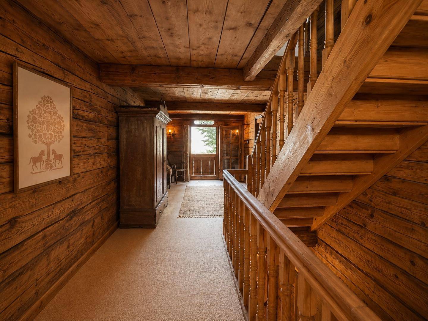 Geräumiger Flur mit Holzvertäfelung, Treppe und Blick auf einen Balkon, der viel Licht hereinlässt.
