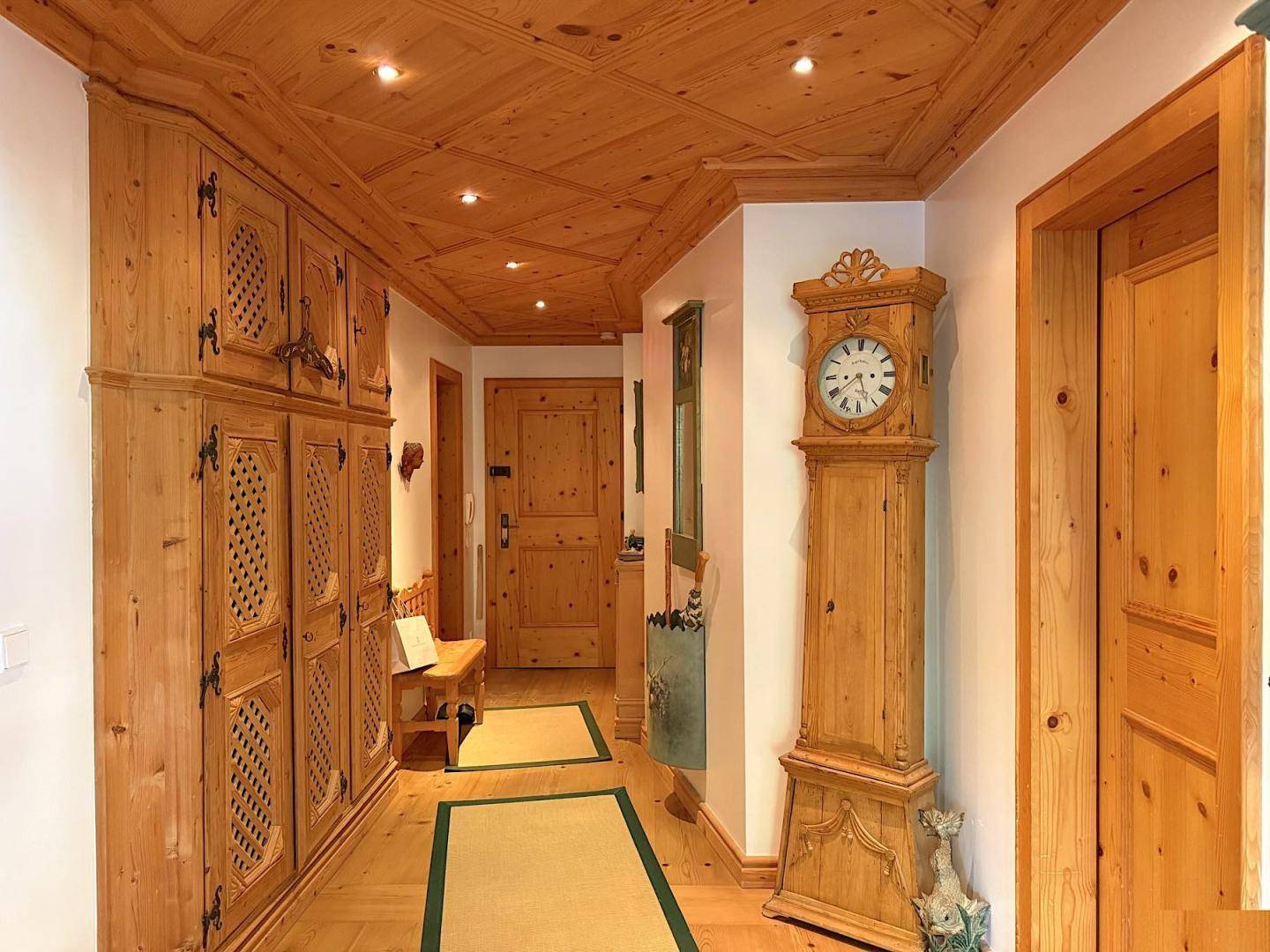Geräumiger Flur mit Einbauschränken aus Holz, Standuhr und dekorativer Holzdecke.