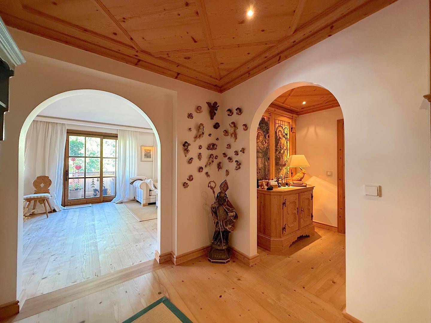 Heller Eingangsbereich mit Rundbögen, Holzboden und Blick in den Wohnbereich.