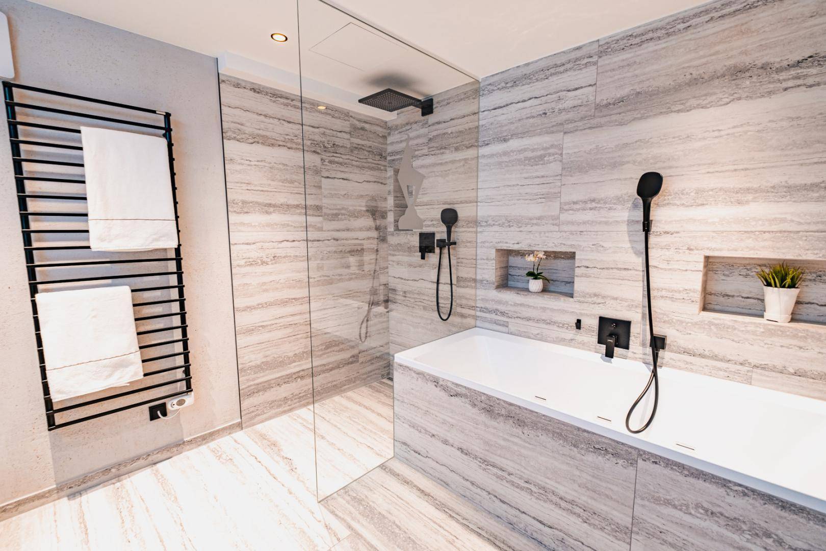 Luxuriöses Badezimmer mit Badewanne, begehbarer Dusche und beheiztem Handtuchhalter.
