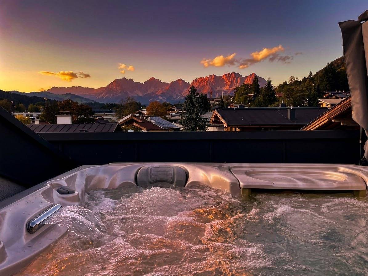 Luxuriöser Whirlpool auf der Terrasse mit spektakulärem Bergblick bei Sonnenuntergang.