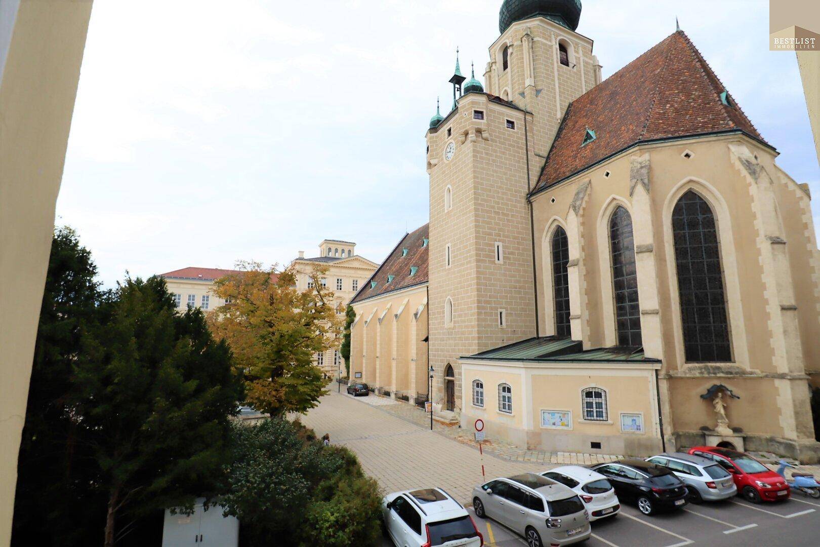 Blick auf eine historische Kirche mit Parkplätzen und umliegenden Gebäuden in der Nachbarschaft.
