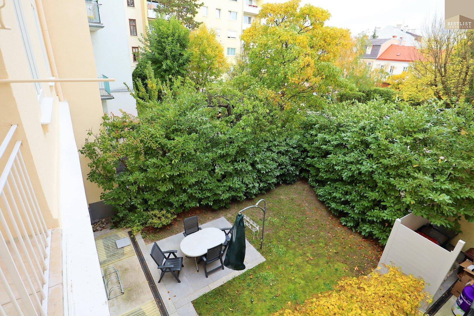 Grüner Innenhof mit Sitzbereich und üppiger Bepflanzung, von oben gesehen, bietet Ruhe.