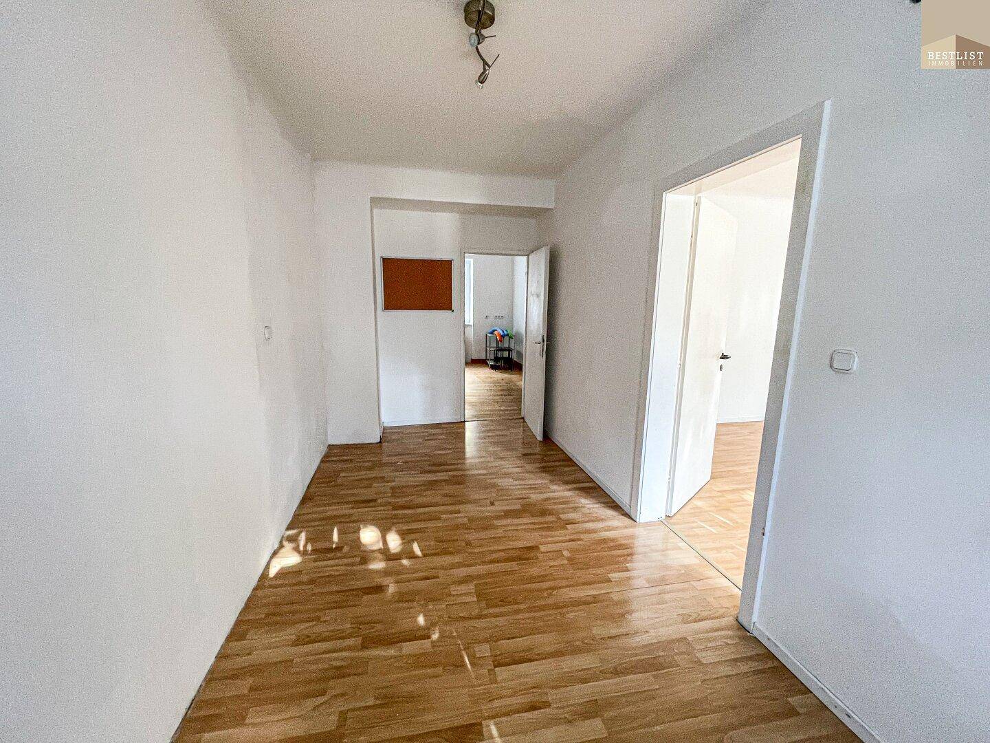Heller Flur mit Holzboden und Zugang zu mehreren Zimmern, gut beleuchtet durch natürliches Licht.