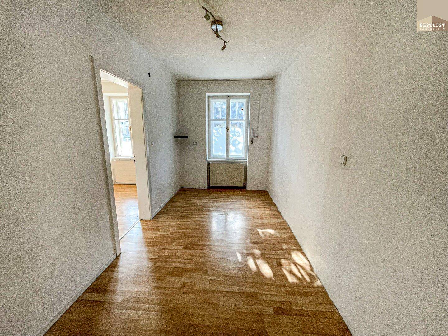 Leerer Raum mit Holzboden und Fenster, ideal für ein Schlafzimmer oder Büro, mit viel Tageslicht.